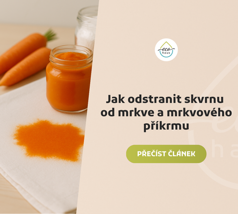 Detailní fotografie bílé textilie se sytě oranžovou skvrnou od mrkvového příkrmu v popředí.