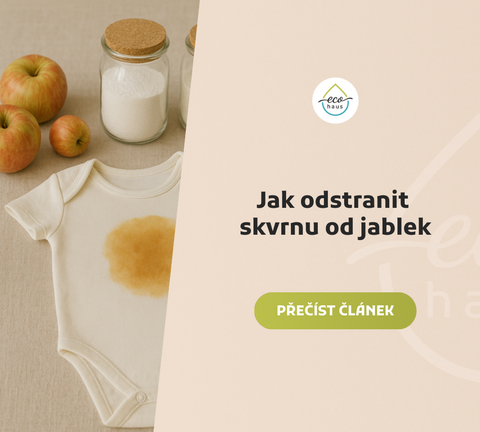 Bílé dětské body s velkou žlutohnědou skvrnou od jablek položené na světlé lněné látce.