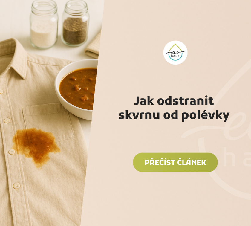 Béžová košile s velkou skvrnou od gulášové polévky položená na světlém dřevěném stole vedle bílé misky s polévkou a dvou sklenic s kořením, nasvícené měkkým přirozeným světlem.